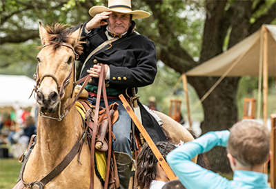 San Jacinto Day historical reenactment - man on horse saluting boy